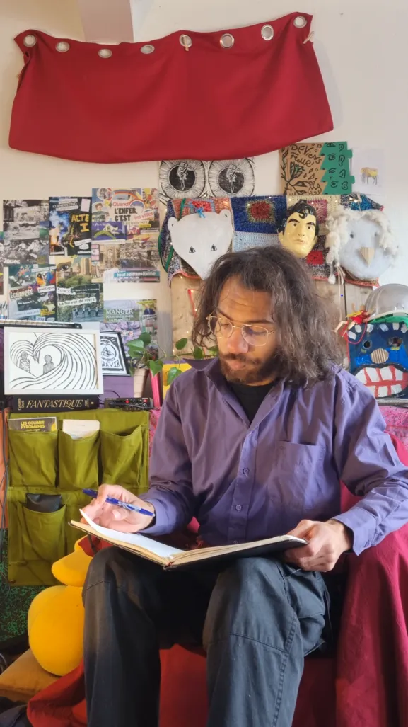 Portrait de Vie, en train d'écrire dans un carnet, dans un intérieur éclectique